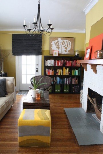 Updated living room. Rainbow bookshelf. Colorful ottomans. Large art.