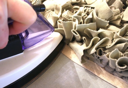 Binding the edge of the rug with iron-on fabric.
