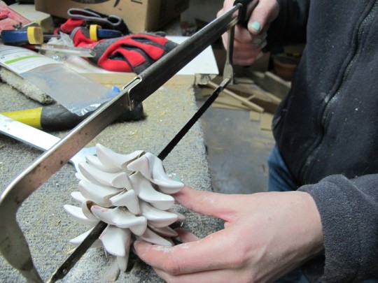 Severing the pineapple stem with a hacksaw.