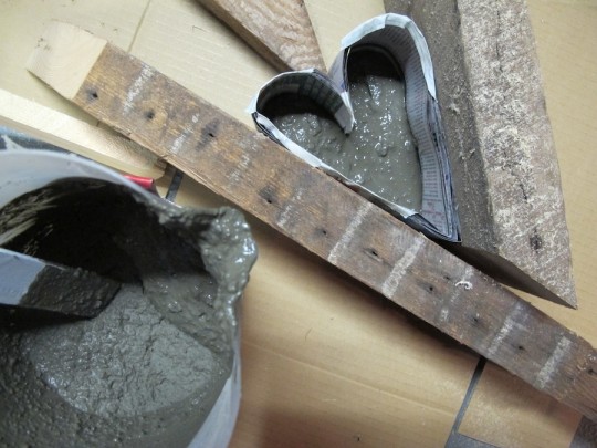 Portland cement mixed thick, being poured and scooped into the mold.