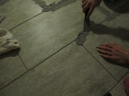 Using a putty knife to gently install grout.