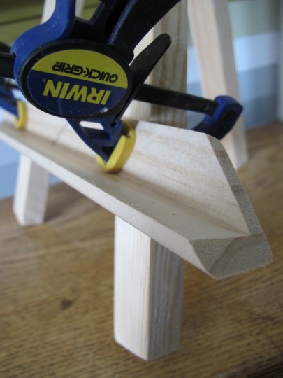 Clamping a piece of corner guard onto the easel legs.