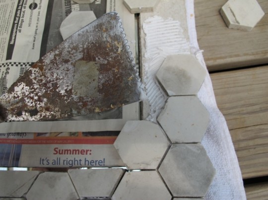 Using mastic to secure the tiles to the cement board.