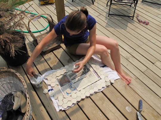 Placing the marble tiles on the mirror frame.