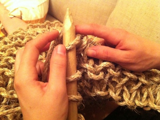 Awkwardly knitting with huge needles.