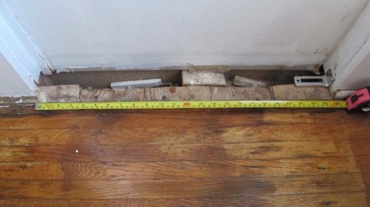 Measuring the doorway for new hardwood floorboards.