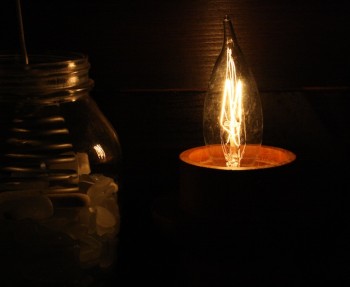 DIY electric candlestick using an upcycled wooden base and length of electrical wire.