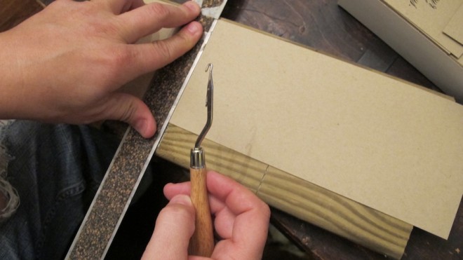 Aligned the paper to the edge of the board, aligned the ruler where the paper needed to be scored, and used a latch hook to crease the paper.