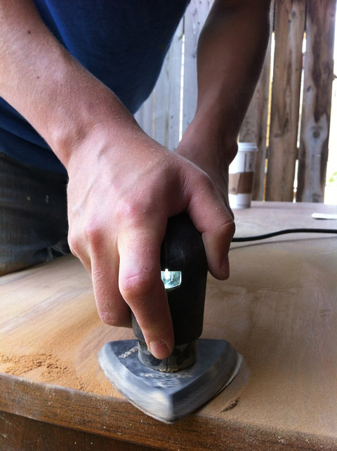 Sanding the topcoats off a wooden furniture.
